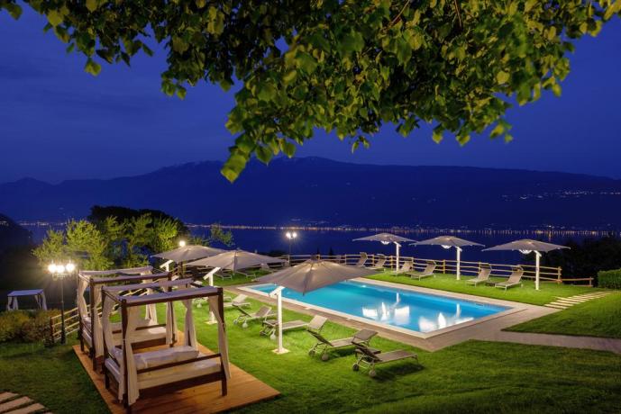 Piscina notturna illuminata con panorama Lago Garda