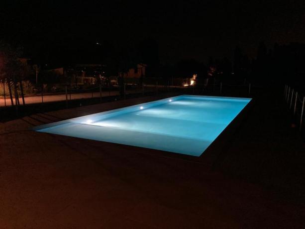 Bellissima piscina illuminata di notte in giardino 