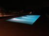 Bellissima piscina illuminata di notte in giardino 